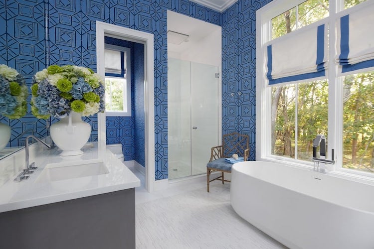 Bathroom with blue painted walls, white tub, and white sink