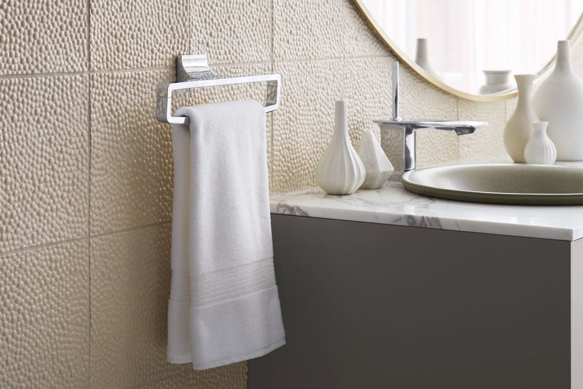 White towel on silver towel rack next to marble bathroom sink