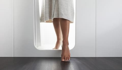 close up of feet in whtie robe exiting the bath stepping over the low step entry